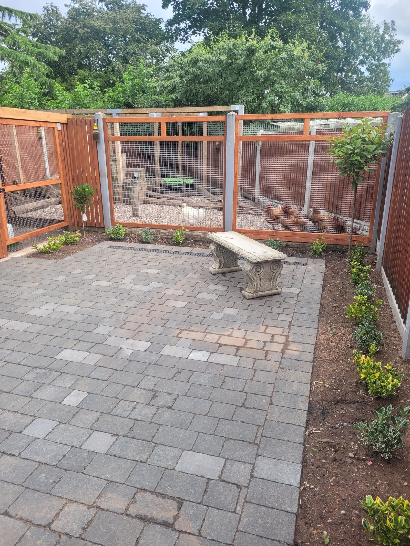 Tumbled-stone patio laid beside a garden bench and fresh planting